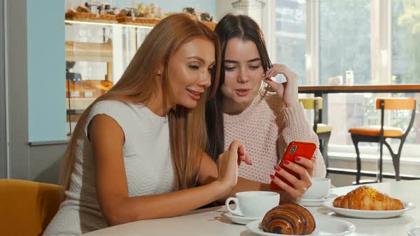 Cheerful Women Laughing To the Camera Using Smart Phone Together