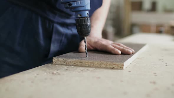 A Hand Master Drills a Hole in the Board