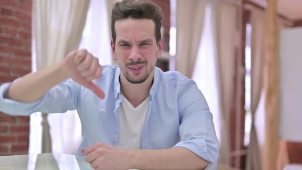 Young Man Showing Thumbs Down at Home