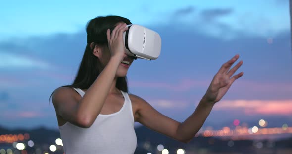 Woman watching on virtual reality device at sunset time 