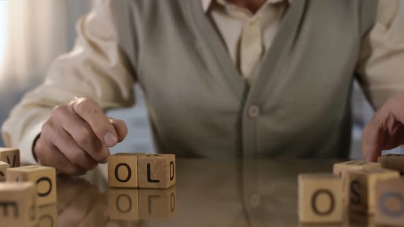 Grandfather Making Word Old of Wooden Cubes on Table, Illness Rehabilitation