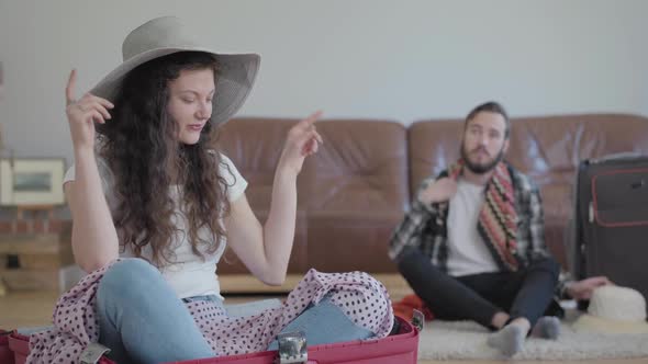 Happy Man and Woman on the Floor at Home Packing a Suitcase Before Travel