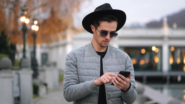 A Man is Going on the Quay and Texting on a Smartphone