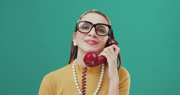 Funny Sixties style woman speaking on a red telephone and making silly faces. Isolated.