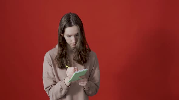 Young Inspired Woman Pensively Thinks and Making Notes in Paper Notebook