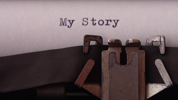 Typing phrase My Story on retro typewriter. Close up.
