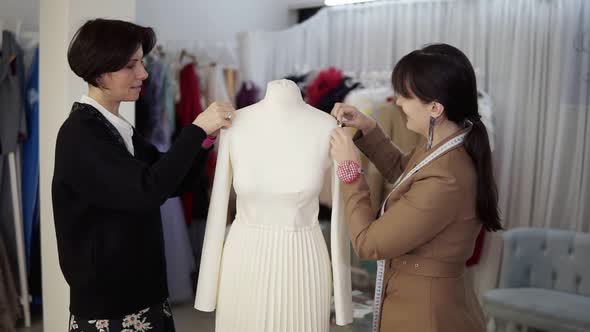 Female Professional Tailors Designers Working with New Model Tailoring White Dress on Mannequin in