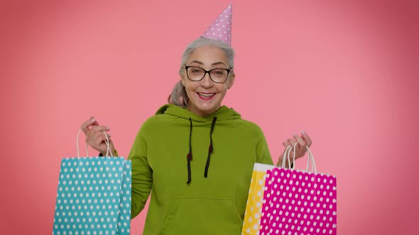 Elderly Granny Woman Showing Shopping Bags Advertising Discounts Looking Amazed with Low Prices