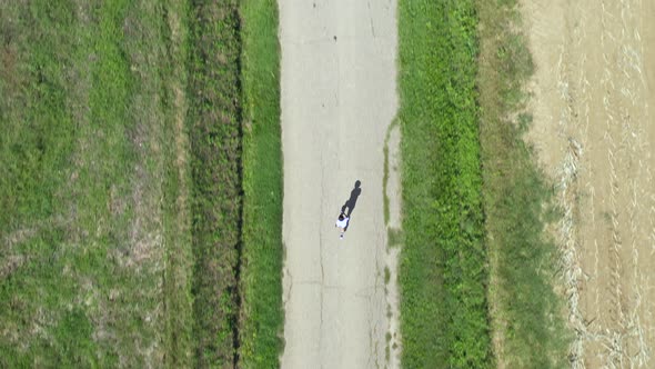 Aerial top view of a little boy running on a countryside road