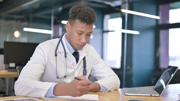 Serious Young Doctor Doing Paperwork in Office 