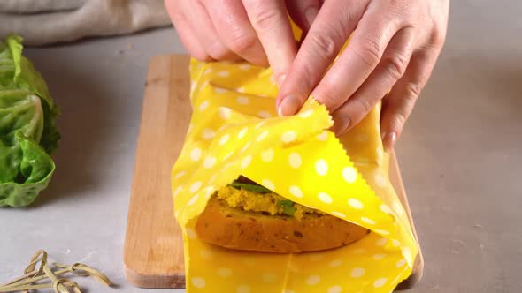 Woman Hands Wrapping a Healthy Sandwich in Beeswax Food Wrap and Cotton Bag