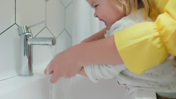 A mother washes her little daughter's hands. Daily hygiene. Close up. Slow motion.