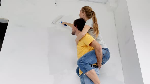 A Happy Man and Woman Paint the Wall Using a Roller Painter