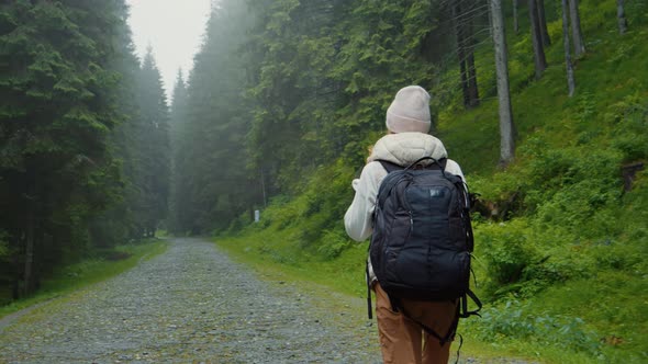 Footage of woman with backpack hiking in the forest.