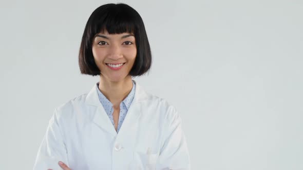 Female doctor standing with arms crossed against white background 