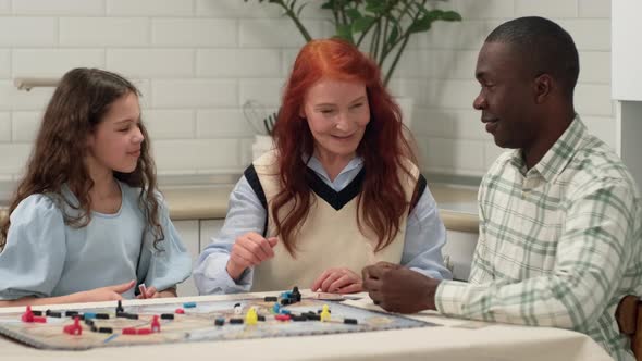 Multi Ethnic Family of Different Age Generations are Playing a Board Game Throwing Dice on the Table