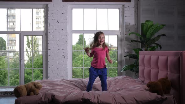 Happy Little Child Jumping on Cozy Bed in Bedroom