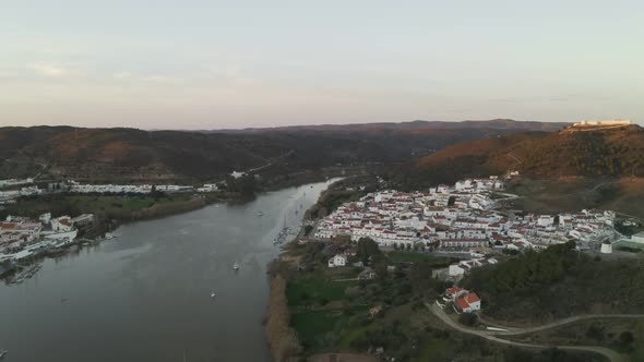 Aerial drone view of Sanlucar de Guadiana in Spain and Alcoutim in Portugal with sail boats on Guadi