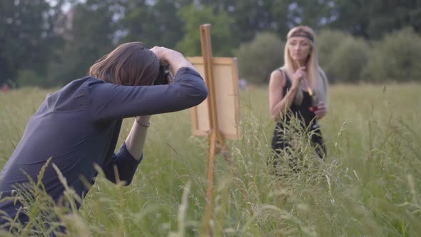 Brunette Caucasian Man Taking Photo of Thoughtful Woman Painting Picture on Canvas. Loving Boyfriend