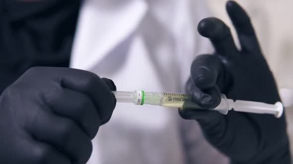 Closwup View of Professional Doctor's Hands in Black Gloves with Medical Syringe in Hands Getting