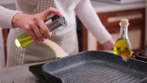Woman Spraying Cooking Olive Oil on the Frying Pan