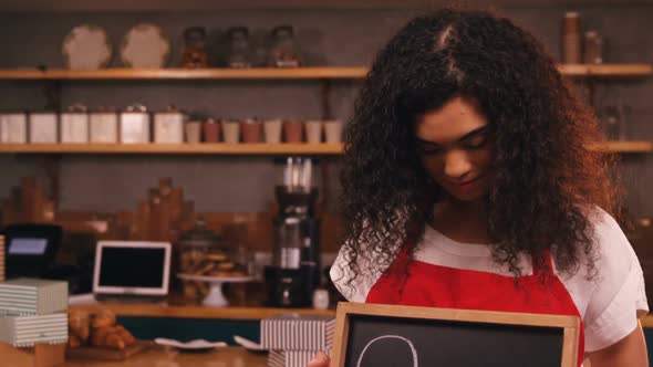 Smiling waitress showing slate with open sign