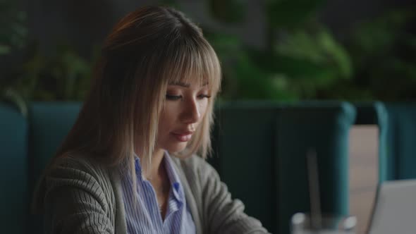 An Asian Woman Sits Brooding and Looks at a Laptop Screen