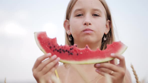 Cute Girl Eating Juicy Watermelon Standing in Wheat Field on Sunny Summer Day