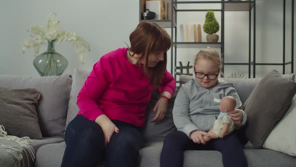 Loving Mom and Girl with Down Syndrome Chatting on Sofa