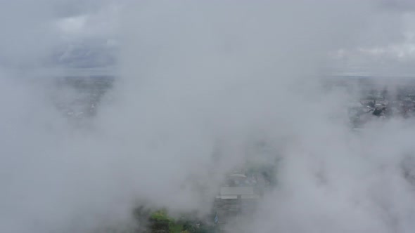 Flying Through a Cloud of Smoke Over a View of a Picturesque Green Town