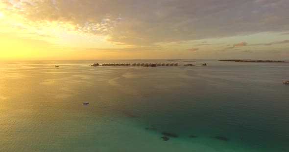 Aerial drone view of a scenic tropical island in the Maldives at sunset.
