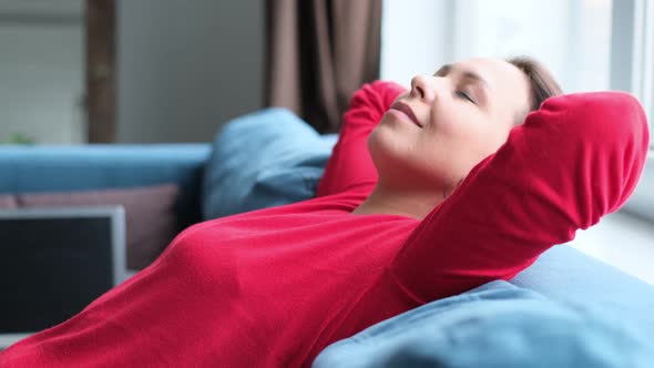 Middleaged Asian Woman in a Red Sweater Taking Deep Breath of Fresh Air Holding Hands Behind Head