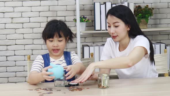 Mother teaches her daughter to save money through a piggy bank