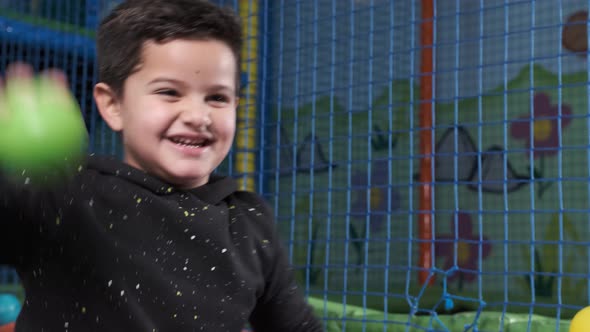 happy 5 year old boy in a ball pool throwing balls. Slow motion