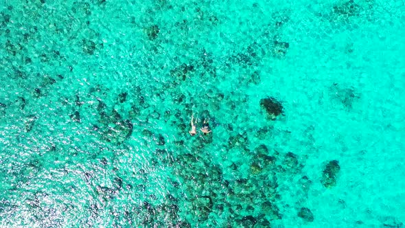 People swim and snorkel on crystal emerald water of turquoise shallow lagoon with beautiful coral re