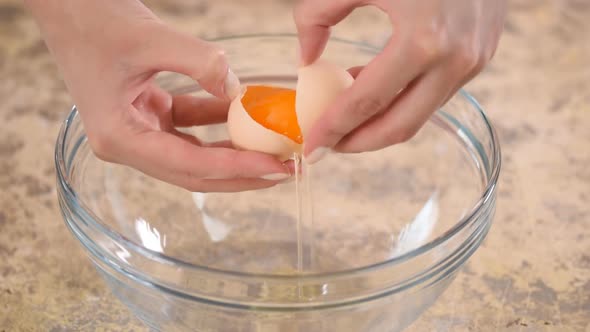 Female Hands Breaking an Egg and Separating Yolk From White