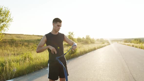 Young Sportsman Wrapping Hand Into Tape Before Workout Outdoors at Nature