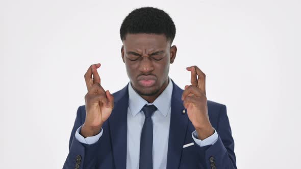 Young Man Praying with Fingers Crossed on White Background