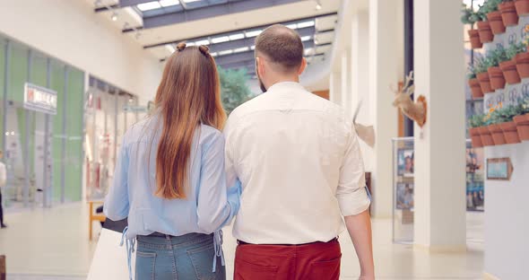 Beautiful Young Couple Worth Walking Along the Shopping Center Holding Hands