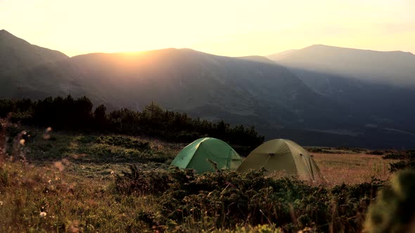 Tourist tent at sunset on the background of a beautiful mountain range. Camp of tourists on the pass