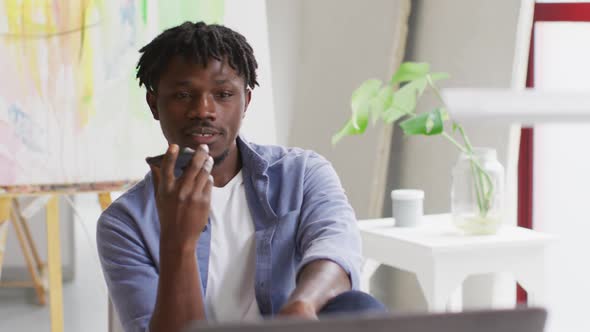 African american male artist talking on smartphone at art studio