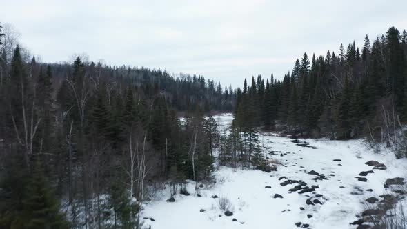 Aerial, person sightseeing on bridge over frozen Poplar River in Lutsen, Minnesota