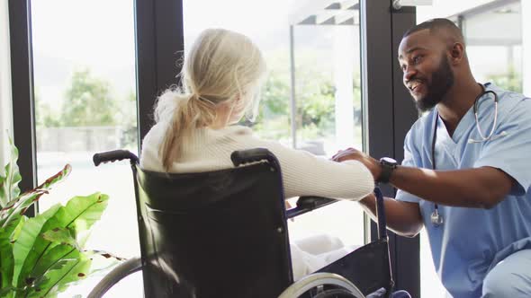 Video of happy african american male doctor taking care of caucasian senior woman