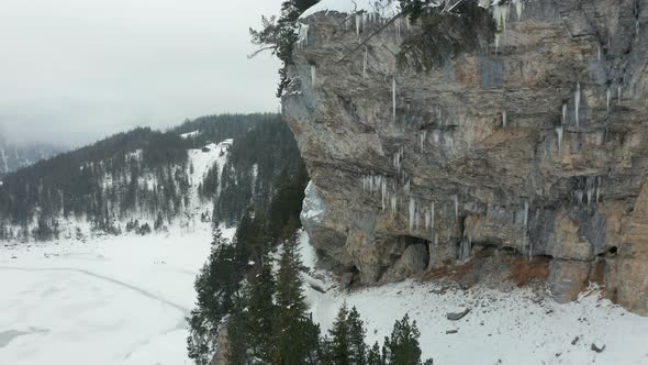 Flying towards icicles hanging of rock mountain wall