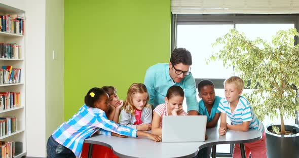 Teacher and kids using laptop in classroom