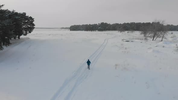 Aerial View of Backpacker Hiking Snowy Trail