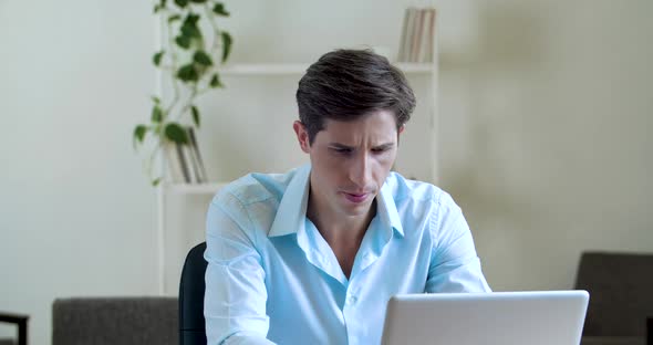 Portrait of Serious Pensive Male Sitting at Desk, Using Laptop To Solve Problem, Search Information