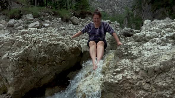 Hiker woman in a rocky valley with spring stream water in the mountain river