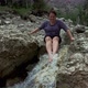Hiker woman in a rocky valley with spring stream water in the mountain river - VideoHive Item for Sale