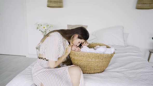 Brunette in Striped Dress Lulls Funny Little Baby in Basket